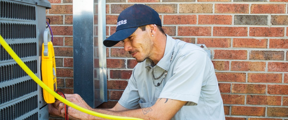 A childers technician performing repair on an outdoor air conditioner
